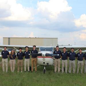 在简斯维尔举行的全国校际飞行协会(NIFA)比赛中，菠菜网lol正规平台精密飞行队的17名成员站在一架飞机前, Wisconsin.